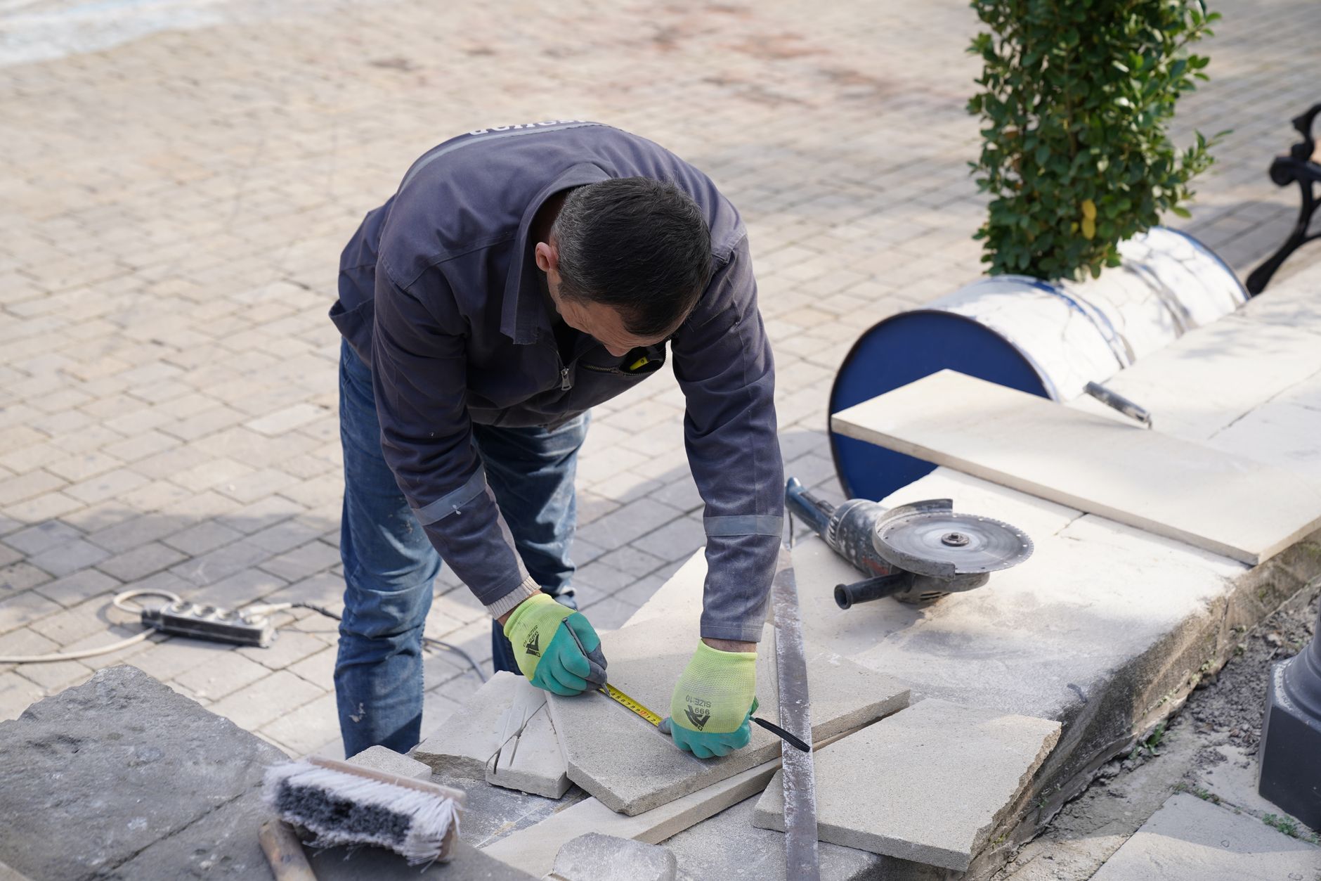Stratenmaker aan het werk op een plein met gezaagde tegels